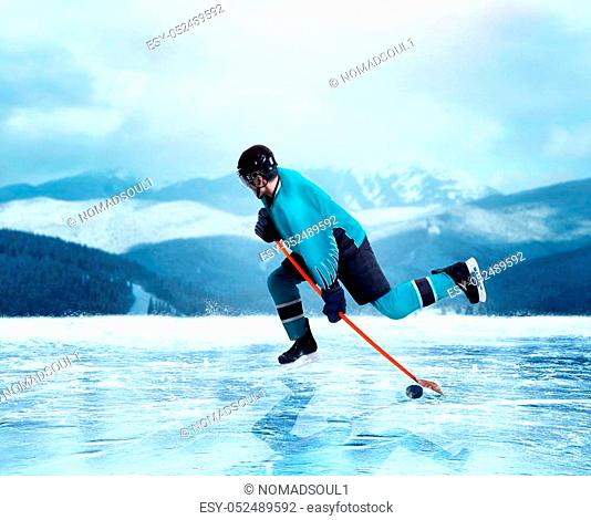 Professional ice hockey player in uniform exercise on frozen lake, winter forest on background. Ice-skating outdoors