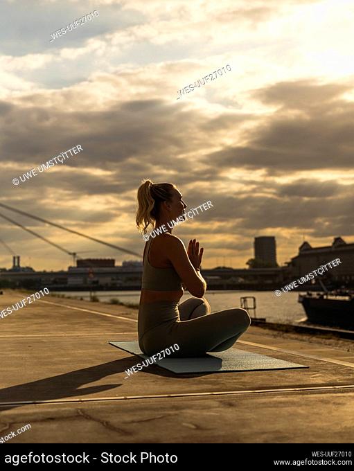 Woman with hands clasped doing yoga at sunset
