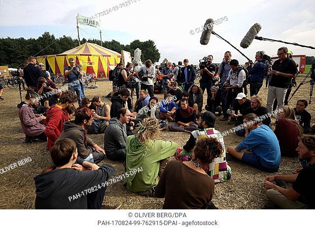 Activists sitting and talking in the Climate Camp near Erkelenz, Germany, 24 August 2017. Representatives of the media stand near-by