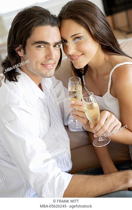 Young couple with champagne glasses on couch