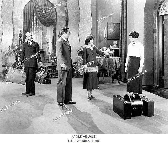 Four people standing in a the lobby of a hotel with luggage All persons depicted are not longer living and no estate exists Supplier warranties that there will...