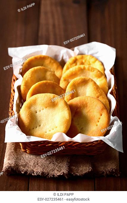 Traditional Chilean Sopaipilla fried pastries made of a bread-like leavened dough served in a basket, photographed on dark wood with natural light (Selective...