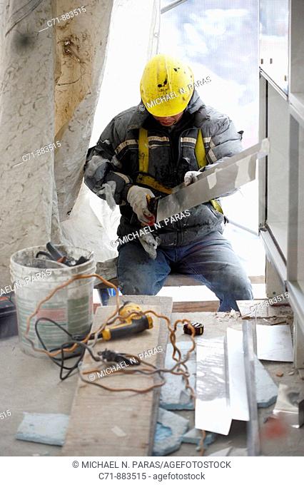 Construction worker cutting tin