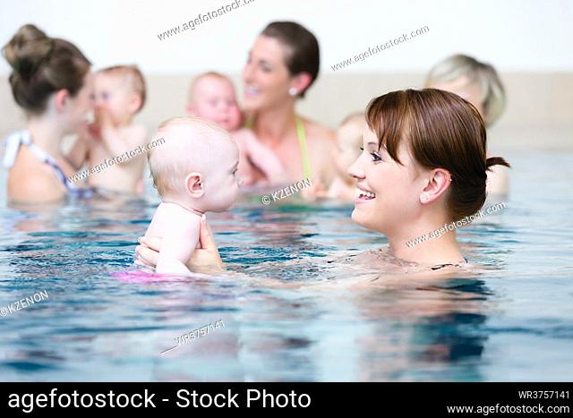 Group of mums with their baby children at infant swimming class