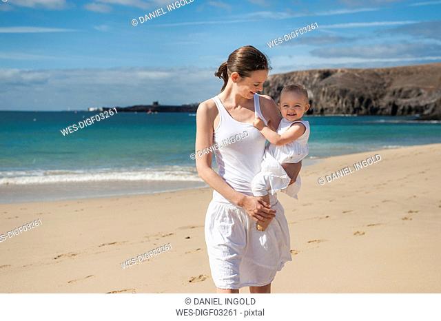 Mother holding little daughter on the beach