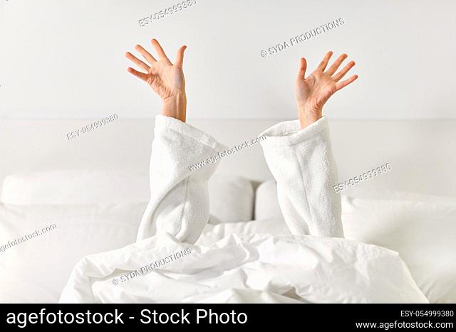 hands of woman lying in bed and stretching