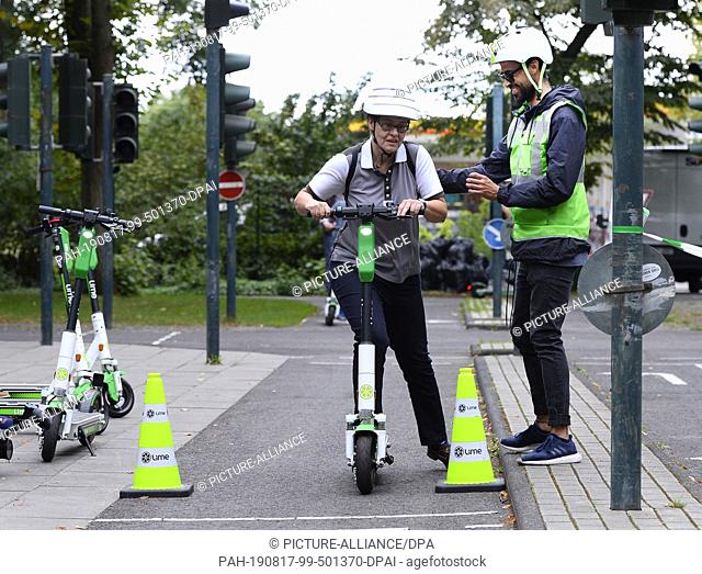 17 August 2019, North Rhine-Westphalia, Cologne: An instructor explains driving to a woman on the youth traffic square during an e-scooter driving safety...