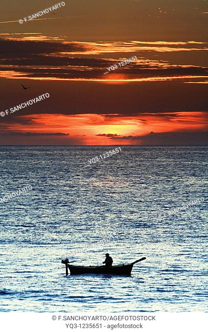 Fisherman in his boat at sunrise. Castro Urdiales, Cantabria, Spain