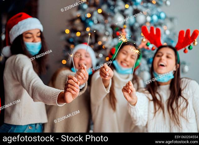 Multi-ethnic young people celebrating New year eve holding sparklers, multiracial friends having fun at party celebration