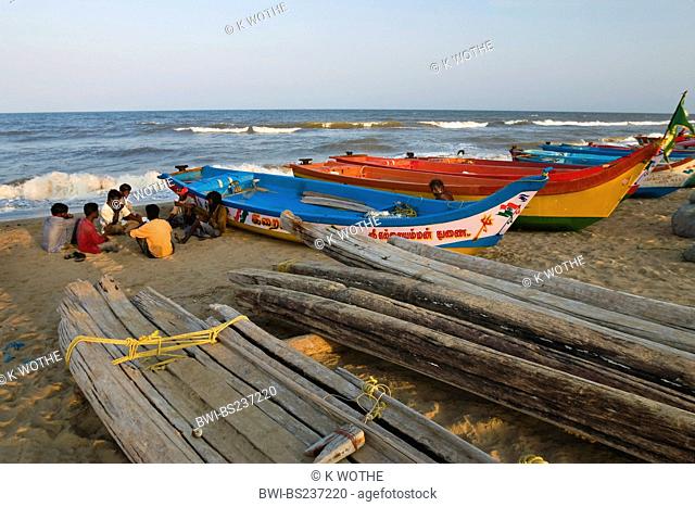 fishermen sitting on sand beach beside their boats, India, Tamil Nadu, Marina Beach, Chennai