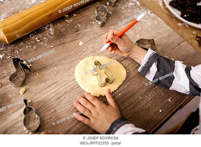 Boy cutting out cookies with tool, partial view