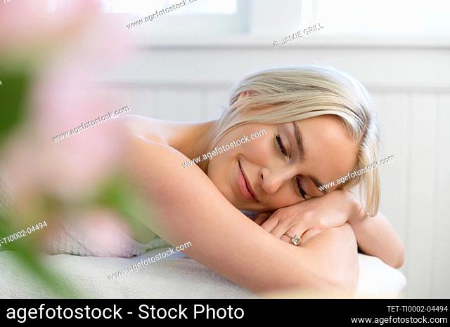 Smiling woman lying with eyes closed on massage table