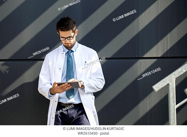 Doctor with eyeglasses using digital tablet outdoors