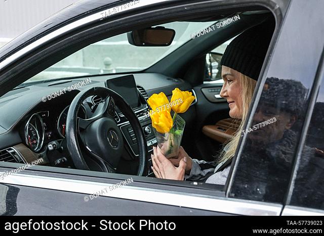 RUSSIA, YEKATERINBURG - MARCH 7, 2023: A woman driver accepts a bouquet of tulips and congratulations from traffic police on 8 Marta Street ahead of...