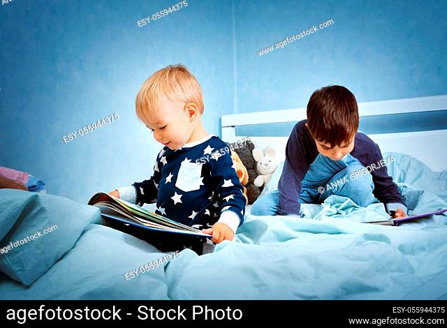 Brothers sitting in the bed in pyjamas and reading books