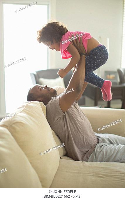 Father and daughter playing on sofa
