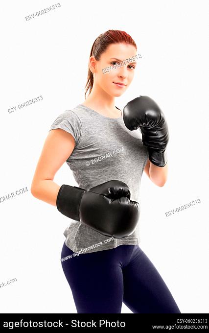 A portrait of a beautiful young girl with boxing gloves in a stance, isolated on white background