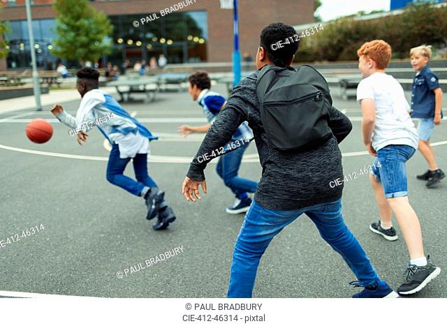 Junior high boy students playing basketball in schoolyard