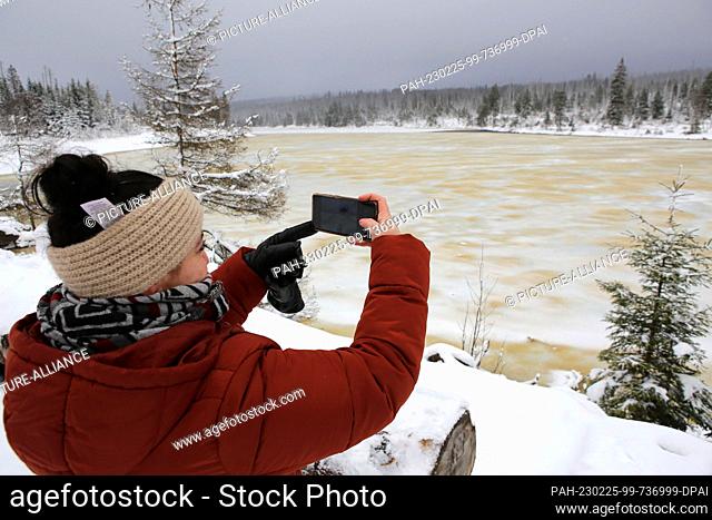 25 February 2023, Lower Saxony, Oderteich: Ouided Majrada-Boy takes a photo of the frozen Oderteich pond in the Harz Mountains with her cell phone