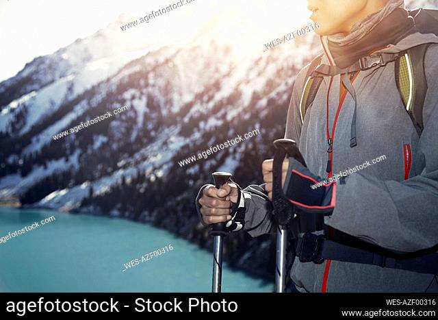 Woman with hiking poles by standing by mountain