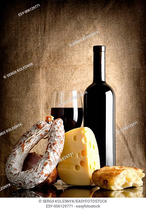 Wine and sausage, bread on an old canvas