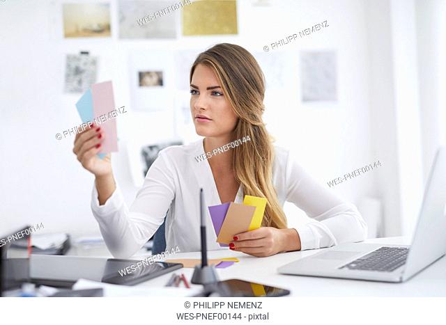 Young woman looking at notes at desk in office