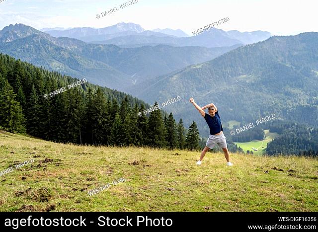 Man stretching while standing on meadow