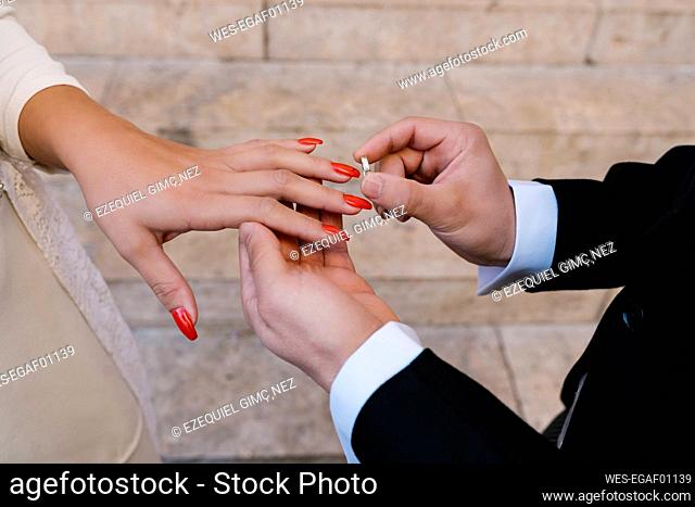 Groom placing ring on bride during wedding day