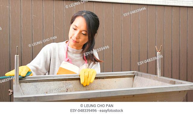 Woman cleaning barbecue stove