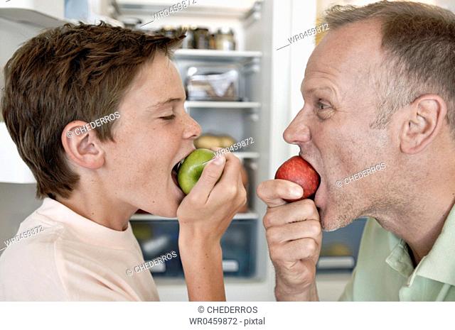 Side profile of a mature man and his son eating apples