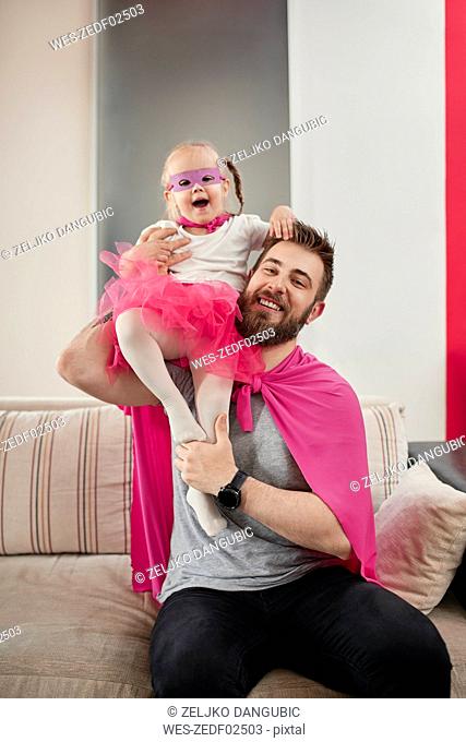 Father and daughter playing superhero and superwoman