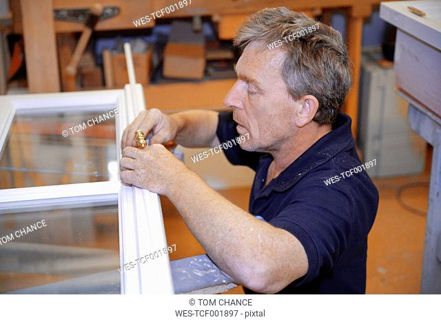Germany, Upper Bavaria, Schaeftlarn, Carpenter fixing window door handle