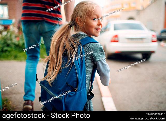 Rear view of father walking back to school with his daughter carrying backpack