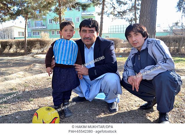 Murtasa Ahmadi wearing rubber boots and a Lionel Messi shirt fashioned from a plastic bag, next to his father Mohammad Arif Ahmadi (c) and his uncle Bismillah...