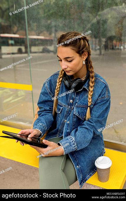 Woman using digital tablet at bus stop