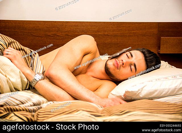 Young Sleepy Man, Lying on his Bed, Eyes Closed Sleeping with a Cellphone on his Ear. He Feel Asleep While Talking