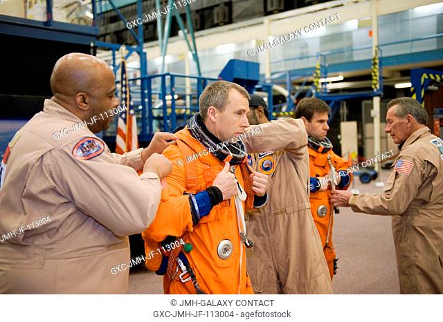 NASA astronaut Andrew Feustel, STS-134 mission specialist, gets help with the donning of a training version of his shuttle launch and entry suit in preparation...