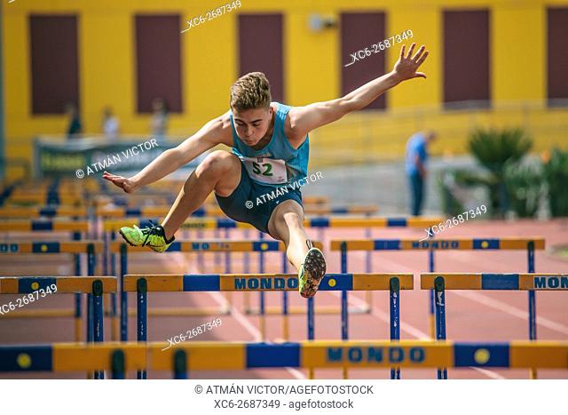 sports boy doing Hurdling on an athletic piste