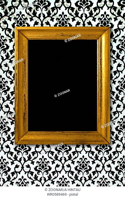 Gold frame on a black and white wallpaper