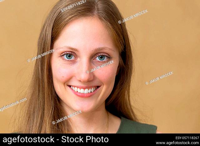 Happy young blonde woman laughing in studio in close up. Beautiful female with white teeth smiling in indoor. Pretty Caucasian long hair model with blue eye...
