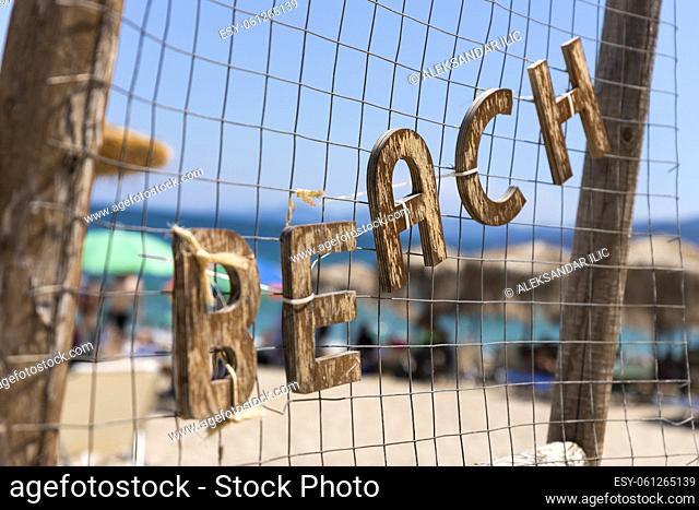 Beach sign. Wooden letters hanging. With sea and beach in background