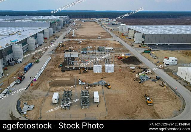 26 March 2021, Brandenburg, Grünheide: The construction site of the Tesla Gigafactory with the production hall (l) and the hall for painting (r