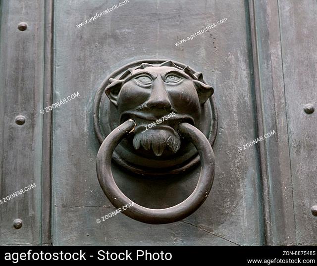 Ornate metal monster head door knocker on a door background