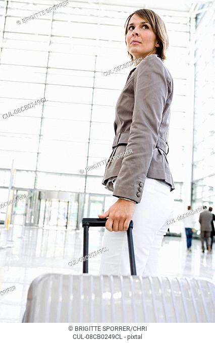 Woman at airport dragging suitcase