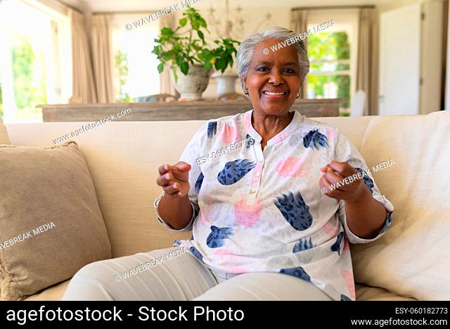 Portrait of senior african american woman sitting on sofa looking at camera and smiling