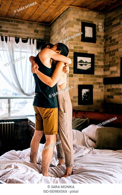 Couple hugging standing on bed