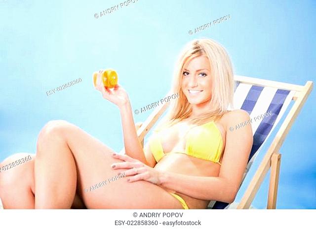 Beautiful young woman in bikini applying suncream