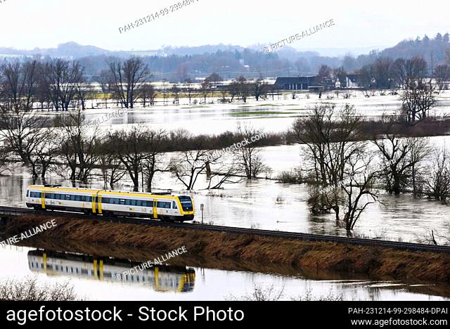 dpatop - 14 December 2023, Baden-Württemberg, Riedlingen: A train travels through an area flooded by the Danube. The flood situation remains tense in parts of...
