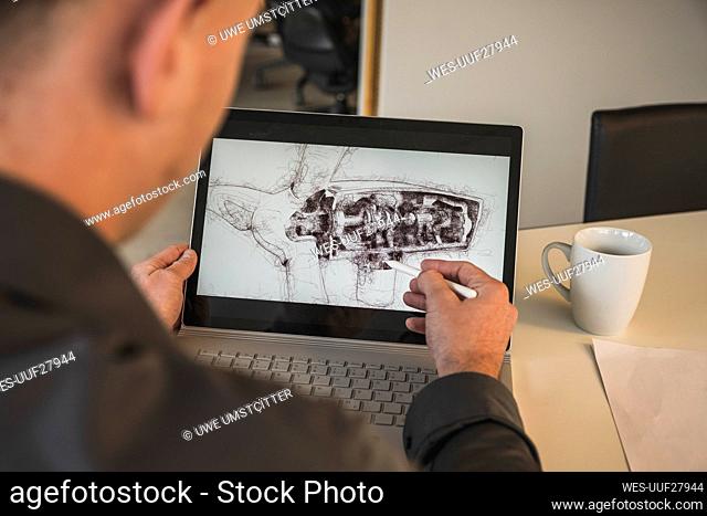 Businessman drawing wind turbine design on laptop at desk