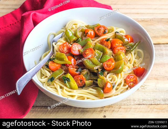 Vegan pasta - Cherry tomatoes, green pepper and basil on spaghetti close up